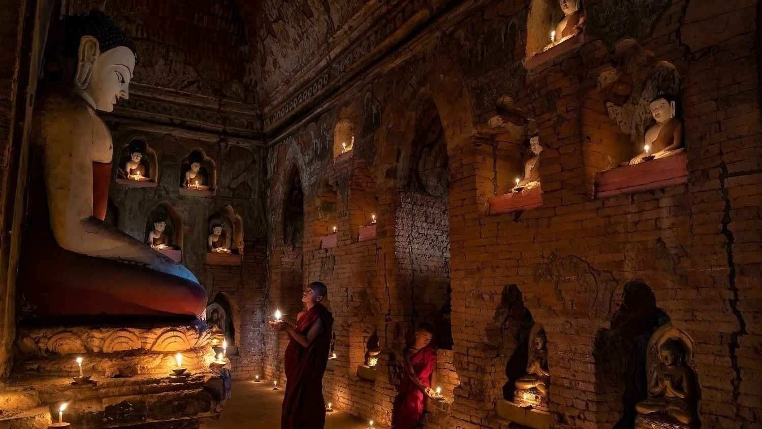 Dua Biksu sedang memberikan persembahan pelita kepada Buddha.