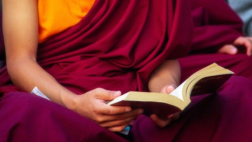 Ilustrasi seorang Biksu sedang membuka buku Dharma.