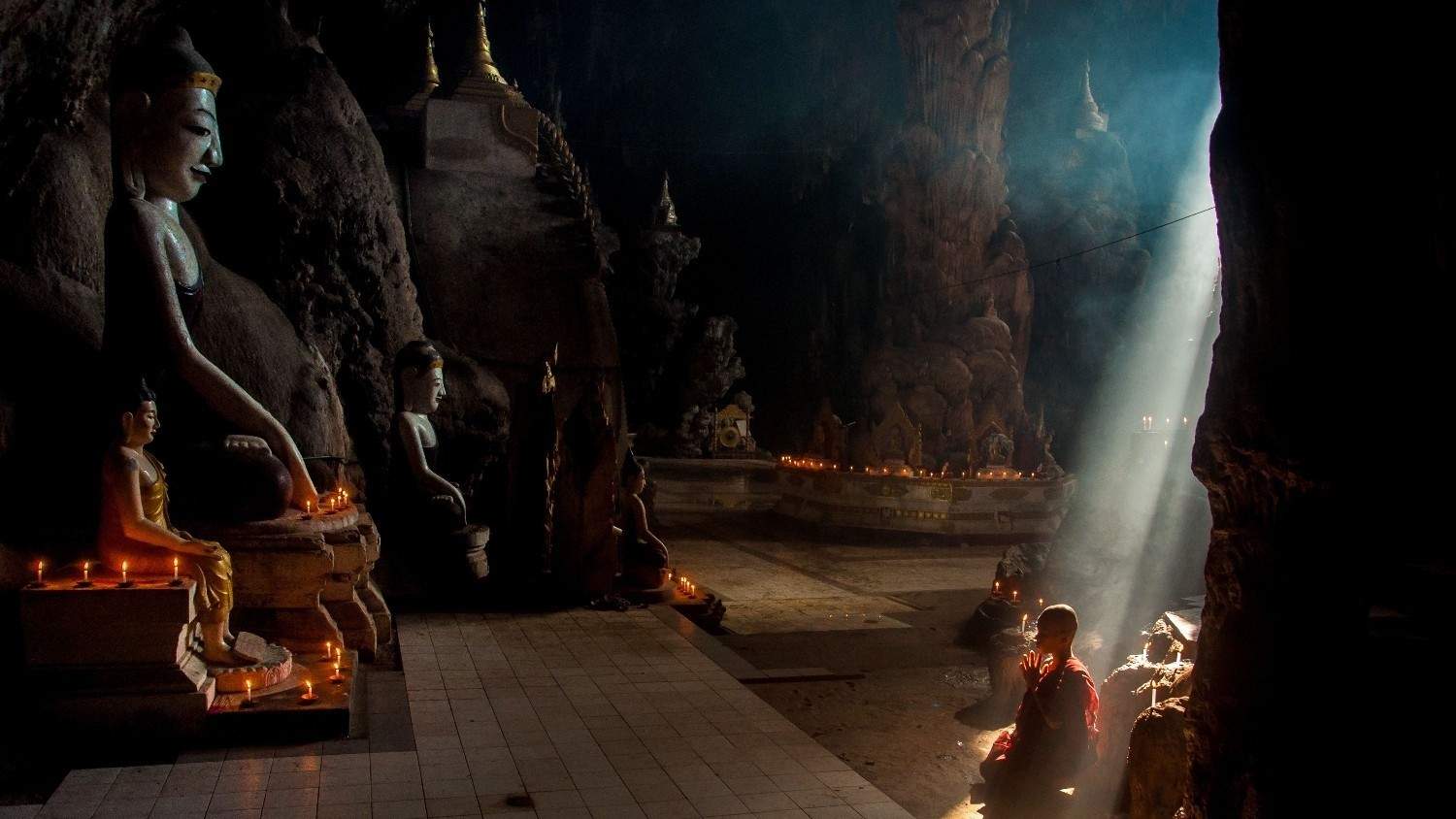 Biksu sedang menatap dan menghormati rupang Buddha sebagai visualisasi kisah Arya Sariputra.
